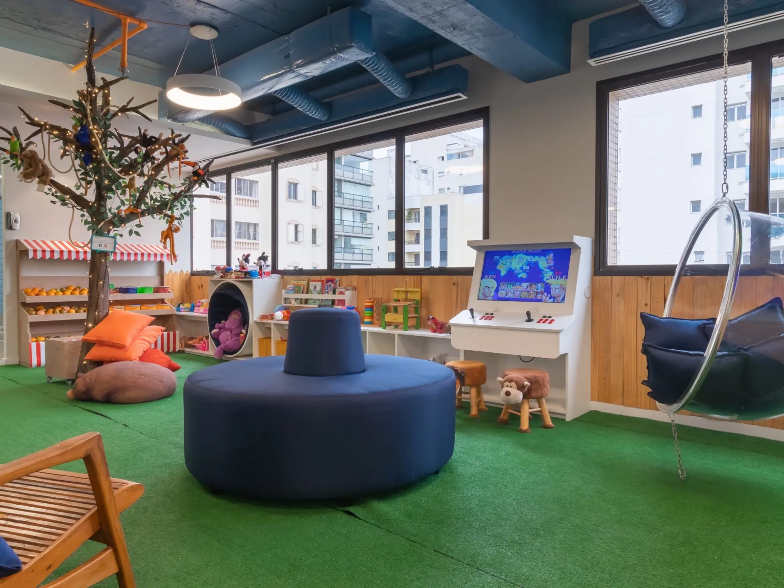 Espaço lúdico infantil da clínica com árvore, brinquedos e área de jogos