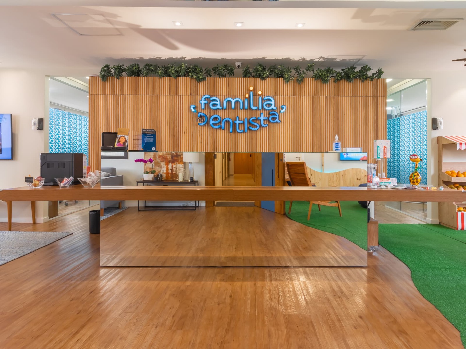 Recepção da clínica com painel ripado de madeira e letreiro Família no Dentista